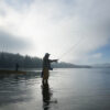 Experience the Thrill of Kenai River Fishing in Alaska Silhouette of fisherman fly fishing for salmon and sea run cutthroat trout in Puget Sound near Olympia, Washington USA.